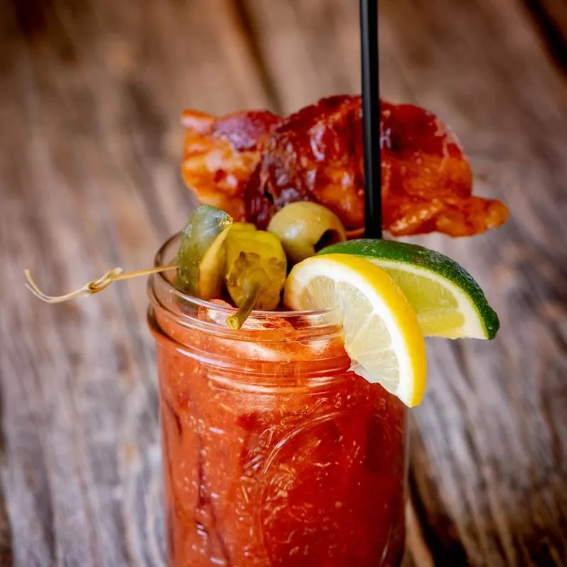 Bacon Bloody Mary garnished with bacon and pickled peppers.